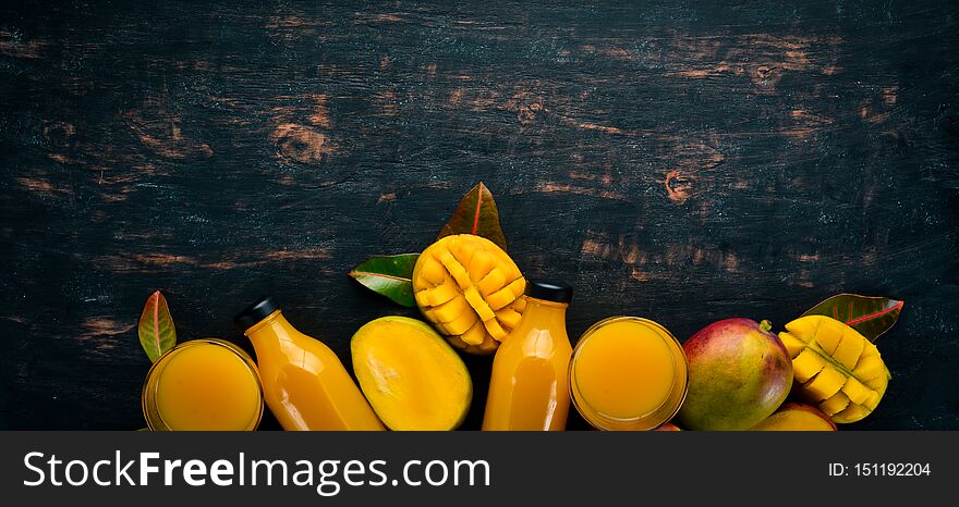 Mango and fresh juice on a black wooden background. Tropical Fruits. Top view. free space for your text