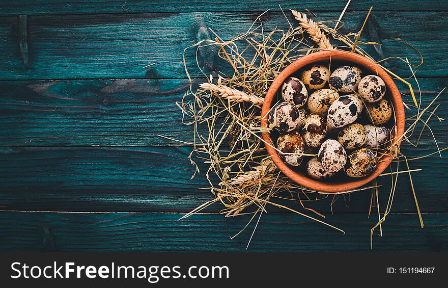 Quail eggs in a wooden bowl. On a wooden background. Top view. Copy space