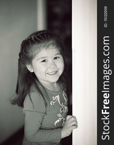 Peeping little girl with charming smile (b&w). Peeping little girl with charming smile (b&w)