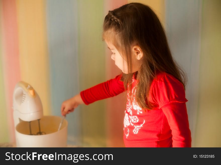 Girl helping her mother to cook apple pie in the kitchen. She is mixing eggs with sugar in the mixer. Girl helping her mother to cook apple pie in the kitchen. She is mixing eggs with sugar in the mixer