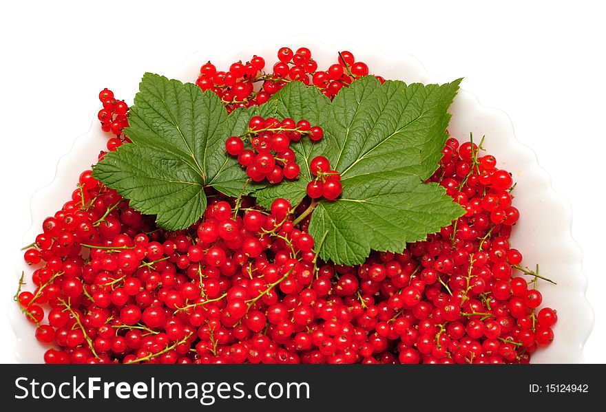 Red berries of currant with green leaves on plate. Red berries of currant with green leaves on plate