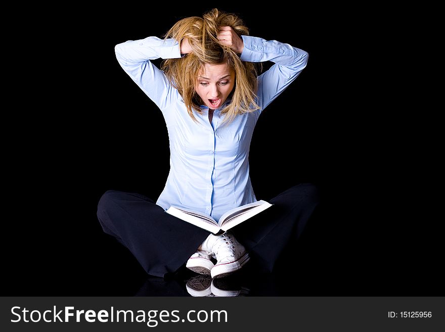 Young female student thrilled and frightened of what she reads in the book, studio shoot isolated on black background. Young female student thrilled and frightened of what she reads in the book, studio shoot isolated on black background