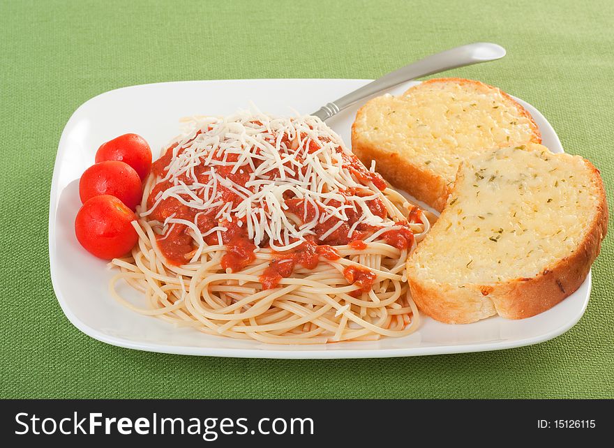 Spaghetti topped with sauce and cheese with cherry tomatoes and cheese toast. Spaghetti topped with sauce and cheese with cherry tomatoes and cheese toast