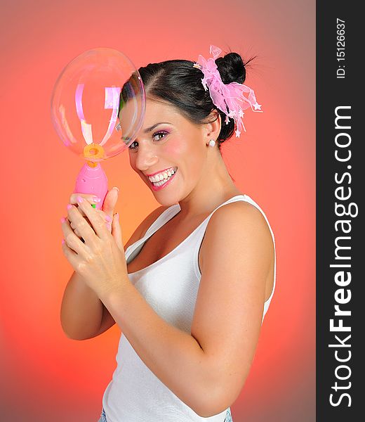 Beautiful happy woman blowing soap bubbles and having fun. pink background