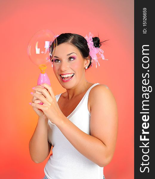 Beautiful happy woman blowing soap bubbles and having fun. pink background