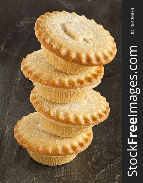 Four apple pies in a stack on a slate background