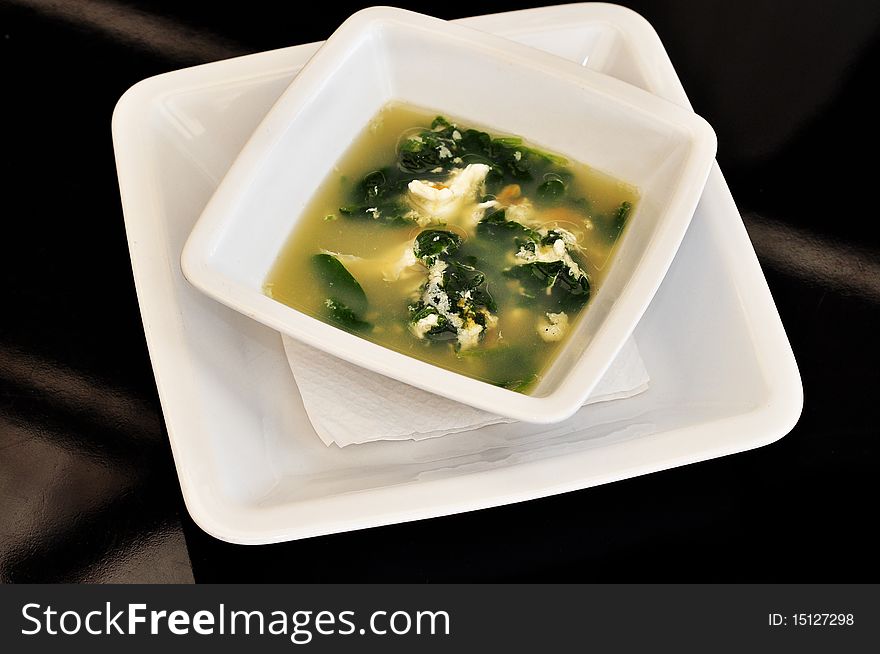 Bowl filled with herb soup and eggs isolated on black background. Bowl filled with herb soup and eggs isolated on black background