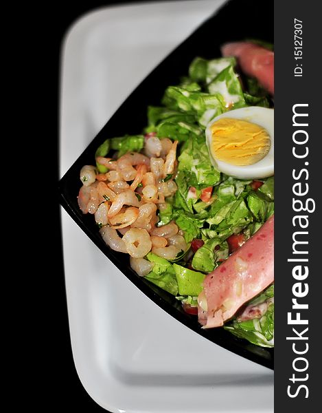 Green salad with ham isolated on black background. Green salad with ham isolated on black background