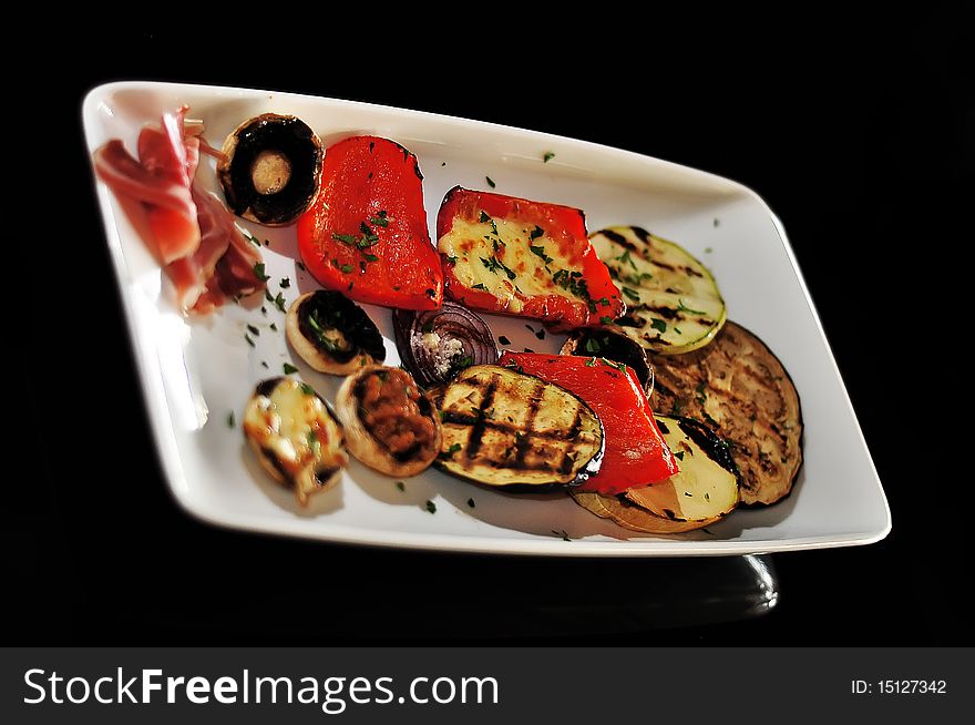 Mushroom appetizer with ham and pepper isolated on black