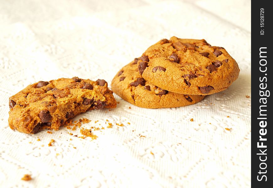 Several chocolate chip cookies, one of them bitten before the photograph was taken.