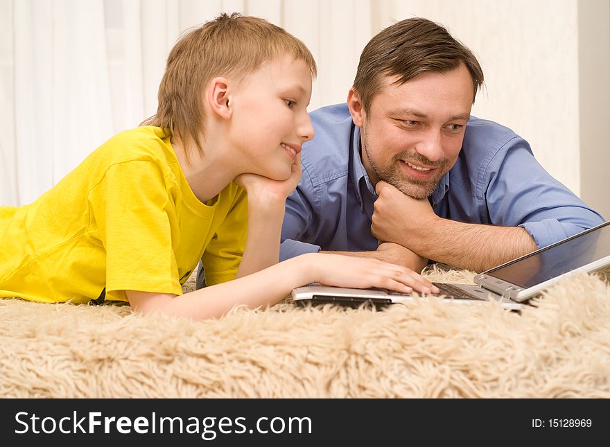 Father and son on the carpet with laptop. Father and son on the carpet with laptop