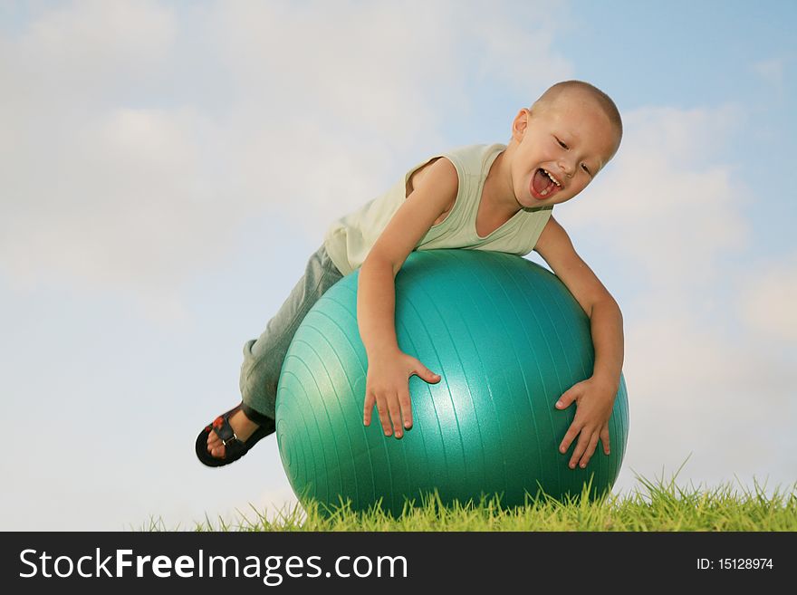 Little white boy fun playing on a gymnastic ball, laughing and enjoying the green grass and the blue sky. Little white boy fun playing on a gymnastic ball, laughing and enjoying the green grass and the blue sky.