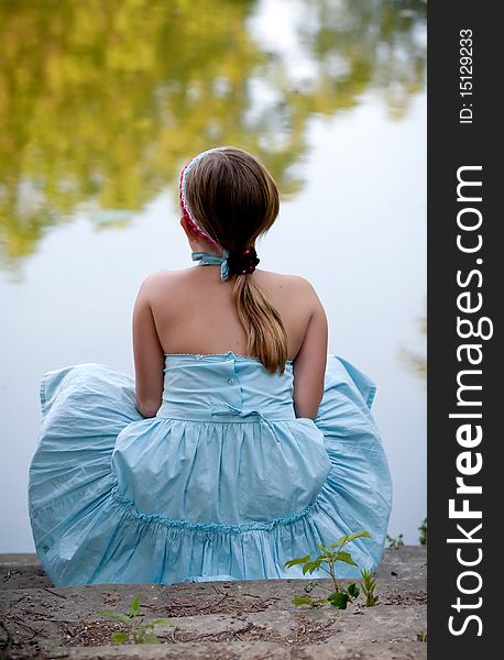 Little girl sitting in park and look at the pond. Little girl sitting in park and look at the pond