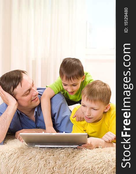 Father with his sons is on the carpet with laptop. Father with his sons is on the carpet with laptop