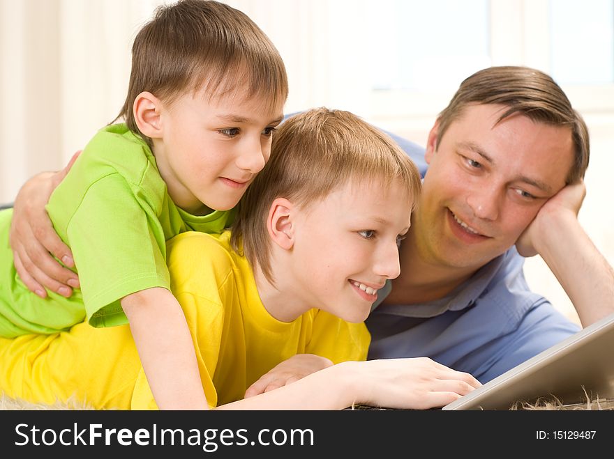Father with  sons is on the carpet with laptop. Father with  sons is on the carpet with laptop