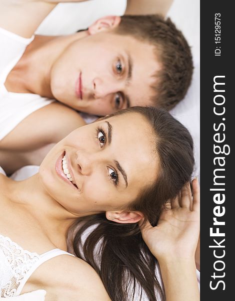 Young smiling couple in a bed on white sheets. Young smiling couple in a bed on white sheets