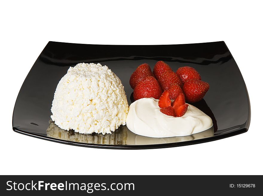 Cheese and strawberries with cream on black plate isolated on white background