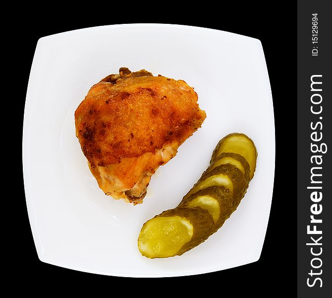 Piece of fried chicken with pickled cucumber on white plate