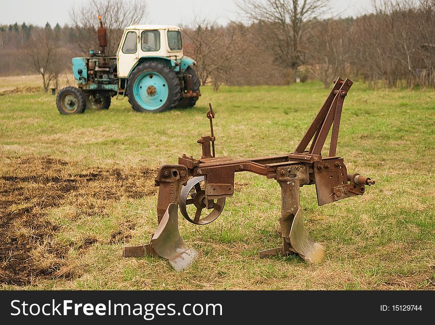 Old plow and tractor in village