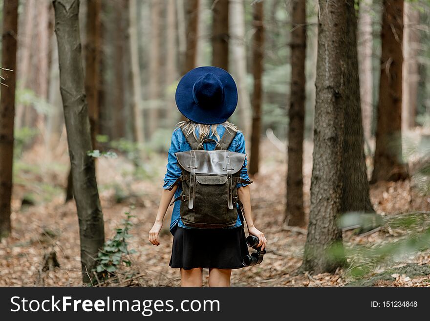 Young woman with binocular and backpack in a forest