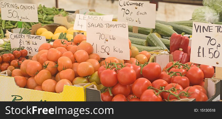 An image of fresh, organic, tomatoes, onions, cucumbers and other salad items for sale on a market stall. An image of fresh, organic, tomatoes, onions, cucumbers and other salad items for sale on a market stall.