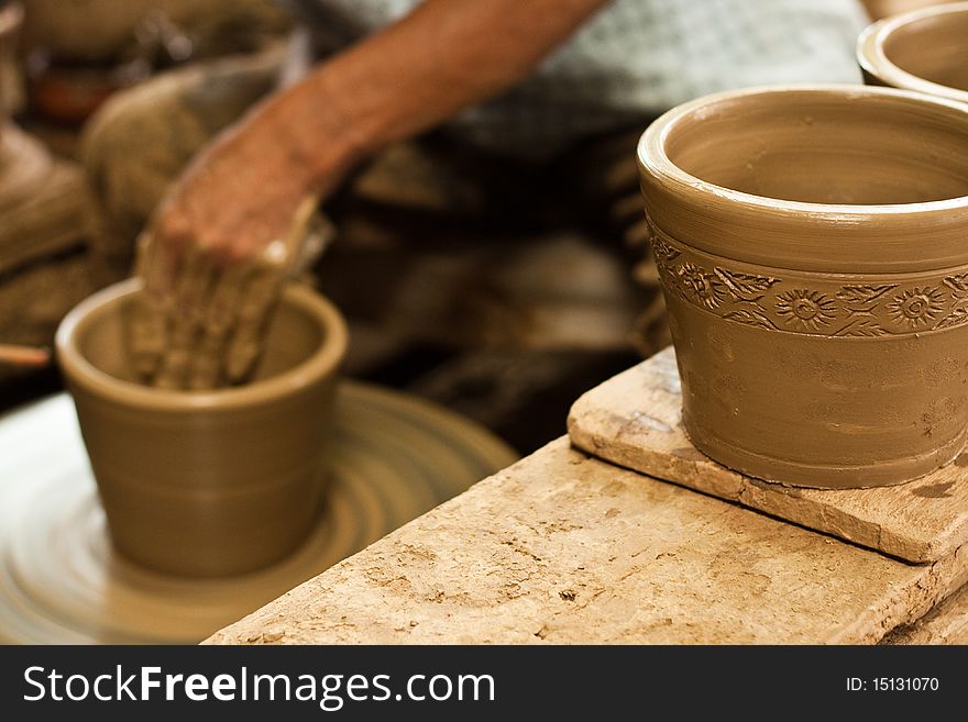 Potter's wheel and hands of craftsman hold a jug