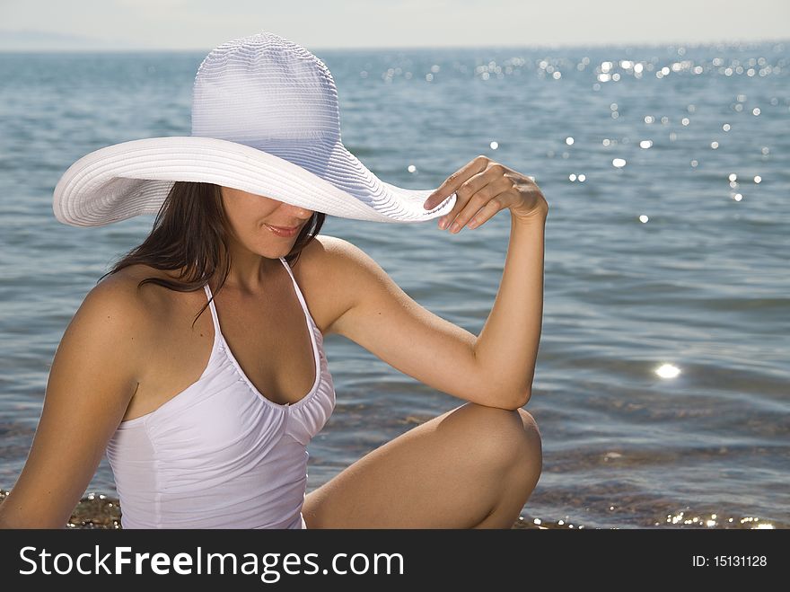 Tanned young girl in a white beach hat against the blue sea. Tanned young girl in a white beach hat against the blue sea