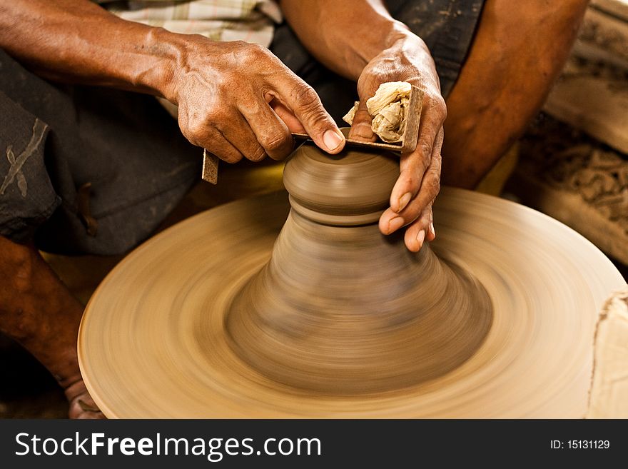 Potter's wheel and hands of craftsman hold a jug