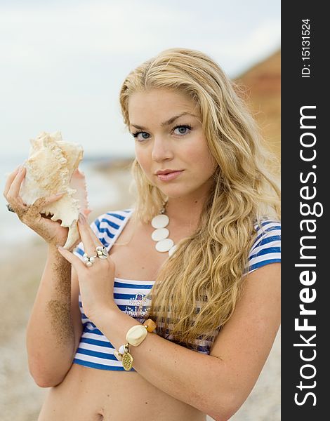 The beautiful girl in a stripped vest  on sea coast with cockleshells