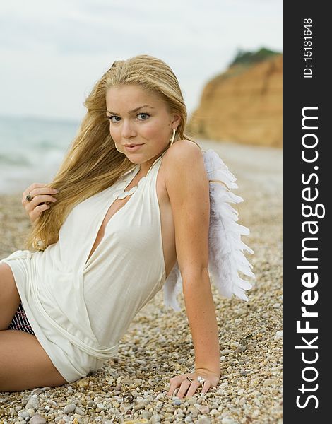 The beautiful blonde with angelic wings on the sea. The beautiful blonde with angelic wings on the sea