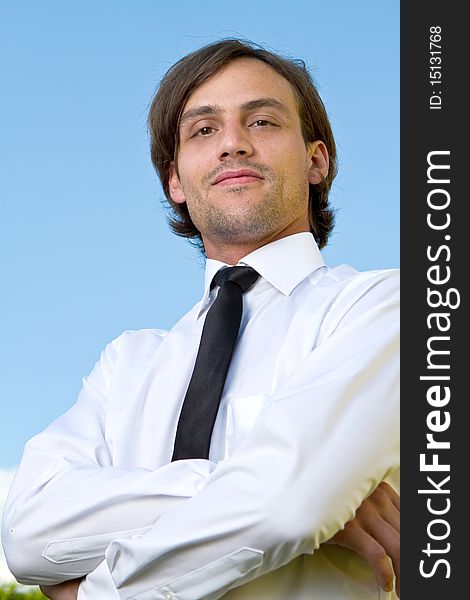 Young businessman with longer hair over a blue sky outside. Young businessman with longer hair over a blue sky outside.