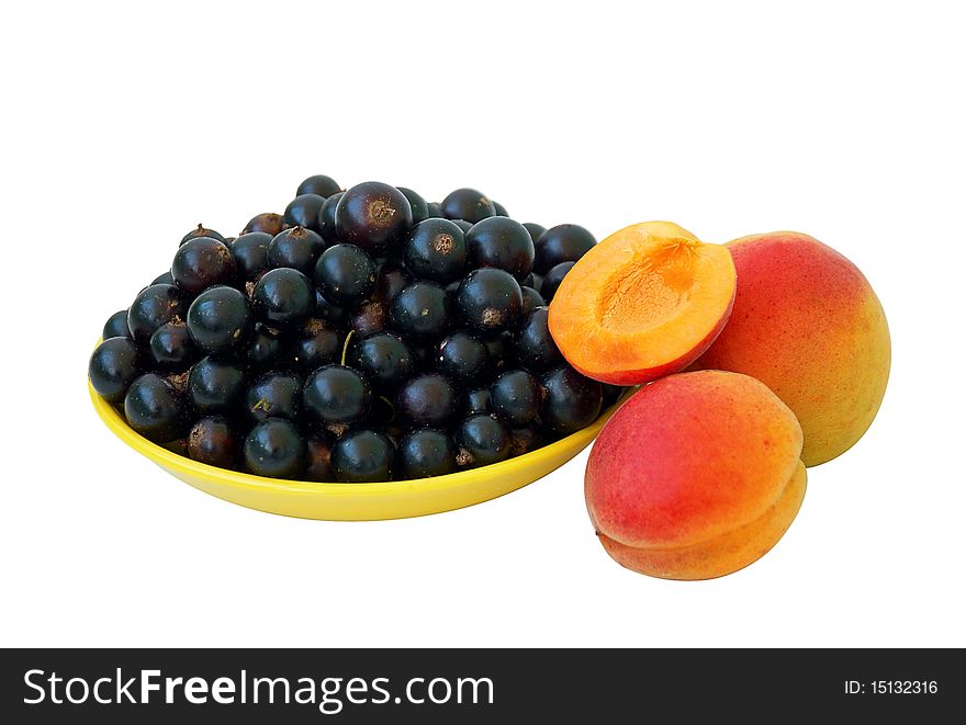 Black currant berries in yellow plate and apricots, isolated on white. Black currant berries in yellow plate and apricots, isolated on white