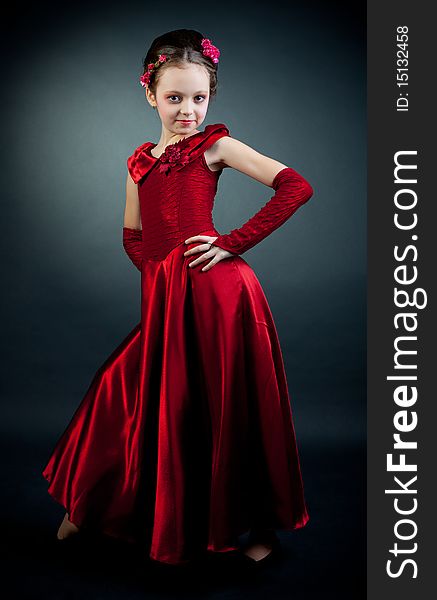 Young model in red dress posing on black background. Young model in red dress posing on black background