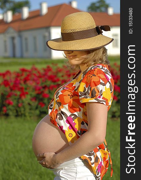 Pregnant woman with hands on the belly in the garden