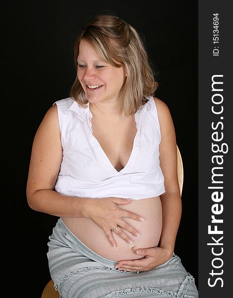 Heavily pregnant blond female sitting on a chair. Heavily pregnant blond female sitting on a chair
