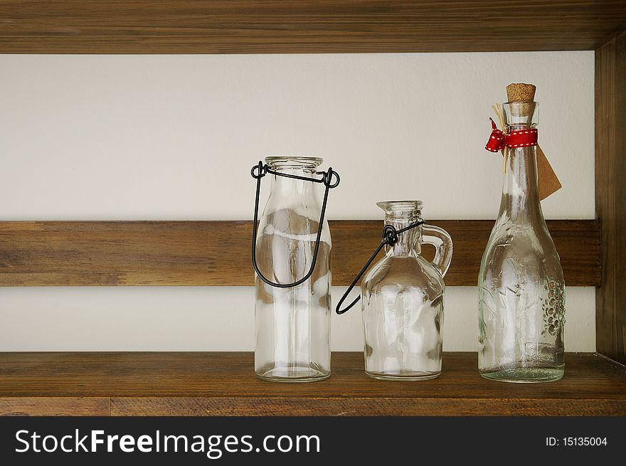 Three decorative bottles on wooden shelf