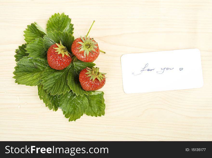 Juicy red strawberries and green leaves on the table next card is the text for you. Juicy red strawberries and green leaves on the table next card is the text for you