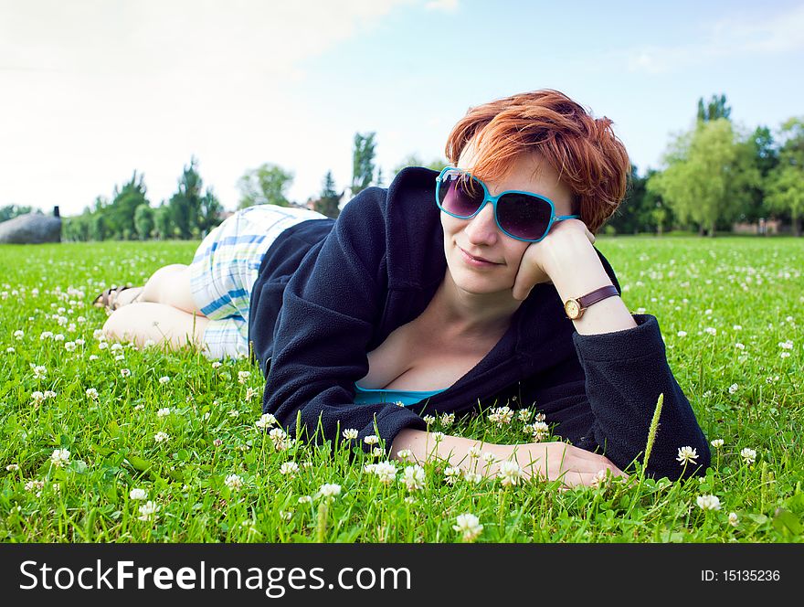 Redhead young woman lying in grass in sunny day. Redhead young woman lying in grass in sunny day