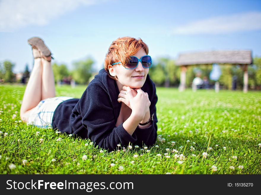 Redhead young woman lying in grass in sunny day. Redhead young woman lying in grass in sunny day