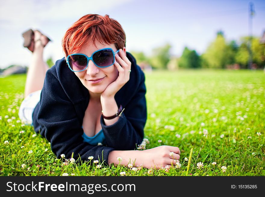 Redhead young woman lying in grass in sunny day. Redhead young woman lying in grass in sunny day