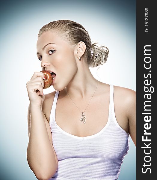 Portrait of young beautiful woman biting apple on blue back. Portrait of young beautiful woman biting apple on blue back