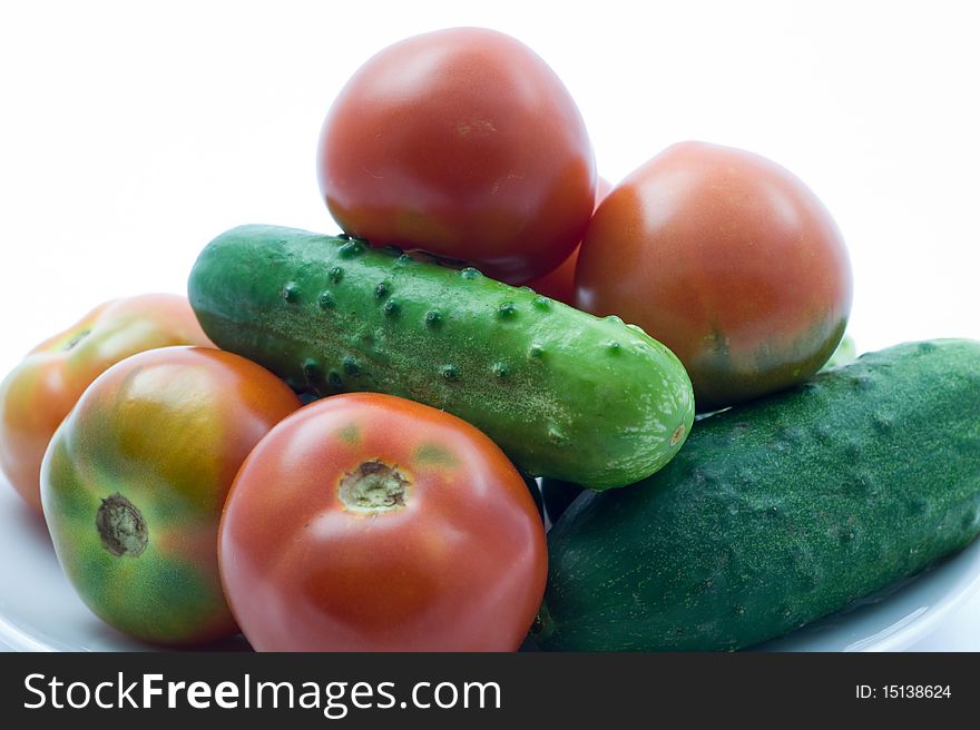 Fresh ripe tomatoes and cucumbers on a white background