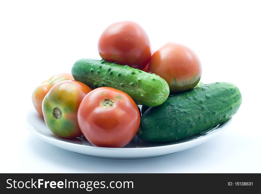 Fresh ripe tomatoes and cucumbers on a plate on a white background