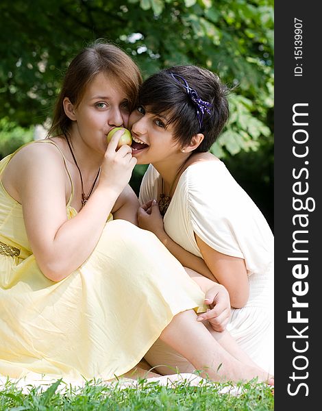 Couple of young pretty girls eating an apple together. Couple of young pretty girls eating an apple together