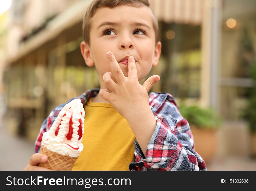 Adorable little boy with delicious ice cream outdoors