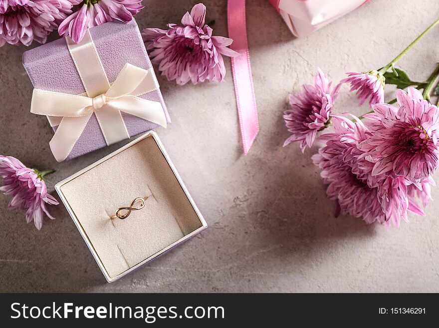 Box with beautiful engagement ring with flowers on table