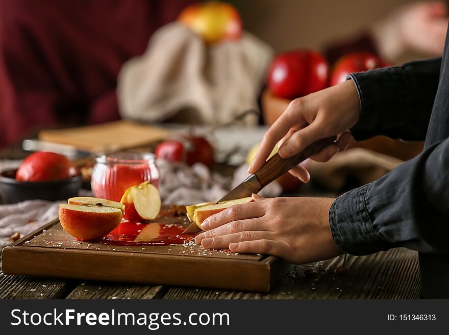 Woman cutting fresh apple at wooden table