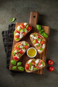Bruschetta With Tomatoes, Mozzarella Cheese And Basil On A Cutting Board. Traditional Italian Appetizer Or Snack Royalty Free Stock Image