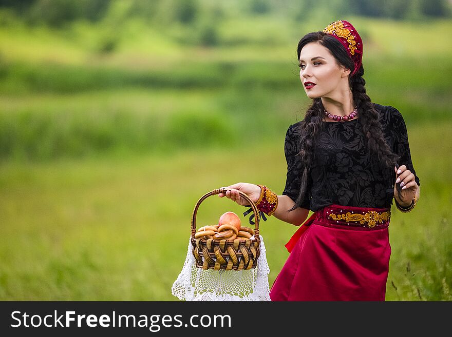 Fashion Portrait of Sensual Brunette In Russian Kokoshnik with Basket of Bread Rings. Posing in Nature Field Outdoors