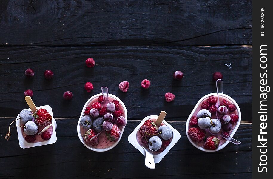 Homemade fresh yogurt. Healthy sweet dessert on dark rustic wooden background. Frozen fruits. Copy space. Homemade fresh yogurt. Healthy sweet dessert on dark rustic wooden background. Frozen fruits. Copy space